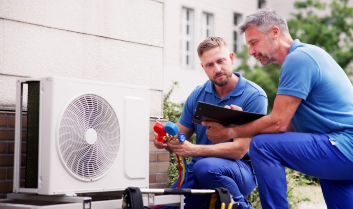 HVAC technicians reviewing an outdoor air conditioning unit in Clearfield, UT