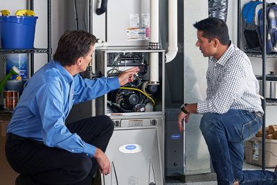 HVAC technician explaining furnace repair and maintenance to a homeowner in Clearfield, UT