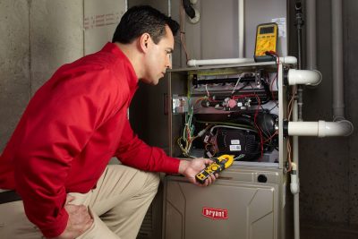 Heating and air conditioning technician servicing an indoor furnace in Clearfield, UT